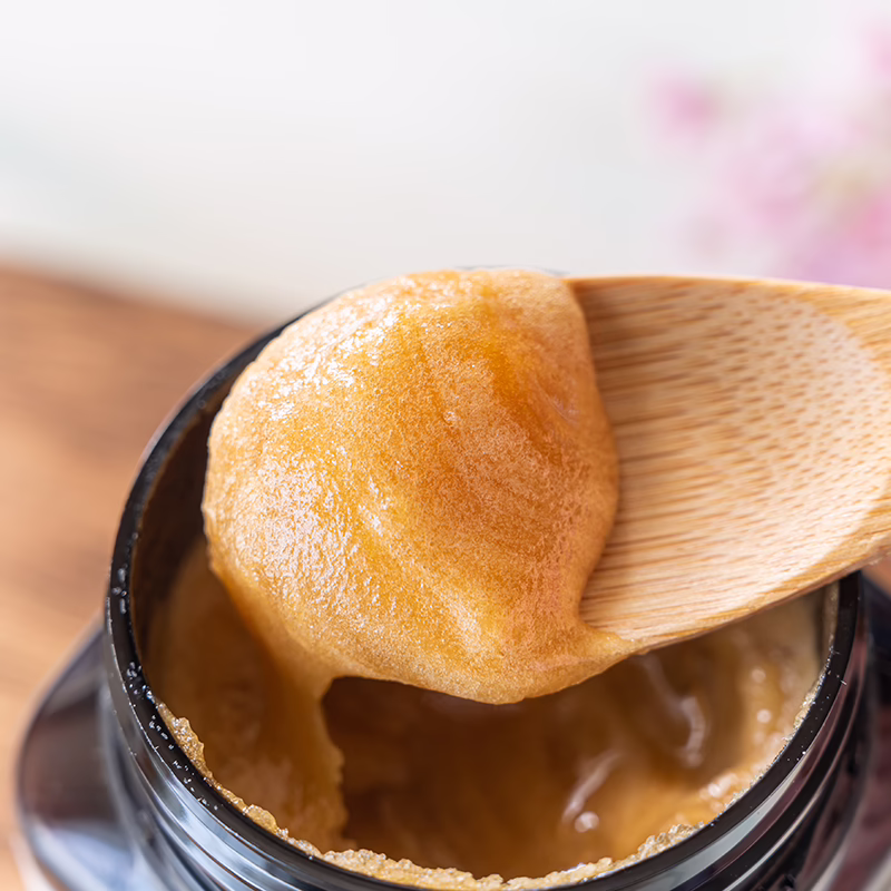 Creamy Manuka honey being scooped from jar with wooden spoon